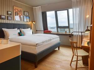 a hotel room with a bed and a desk and a window at 25hours Hotel Paper Island in Copenhagen