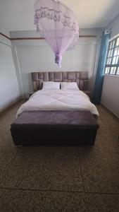 ein Schlafzimmer mit einem großen Bett mit einem Kronleuchter darüber in der Unterkunft MeHomes 1-Bedroom Apartment in Busia