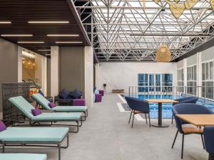 a lobby with chairs and tables and a pool at Mercure Riyadh Al Anoud in Riyadh