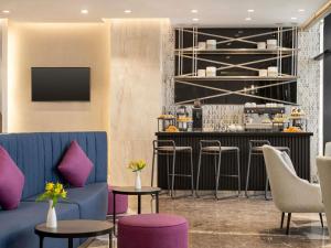 a lobby with a blue couch and a bar with stools at Mercure Riyadh Al Anoud in Riyadh