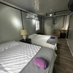 a room with two beds and a chair in it at Orchid Cabin Kuala Tahan in Kuala Tahan