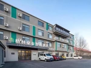 a building with cars parked in a parking lot at GreenTree Inn Express Qingdao Jiaodong International Airport in Ligezhuang