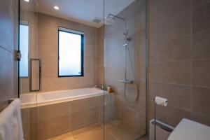 a bathroom with a shower and a tub and a sink at Mokuren by H2 Life in Niseko
