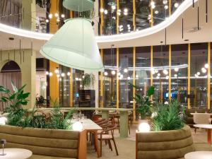 a restaurant with tables and chairs and a large ceiling at Novotel Zagreb in Zagreb