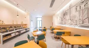 ein Restaurant mit Tischen und Stühlen und einer Küche in der Unterkunft City Comfort Inn Hengyang East Station Linghu Wanda Industry College in Xiantang