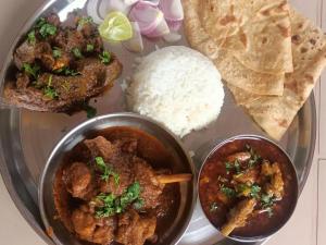 a plate of food with meat and rice and bread at Naksh Villa in Mahabaleshwar