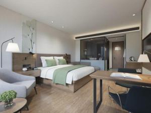 une chambre avec un lit, un bureau et un canapé dans l'établissement GreenTree Inn Express Hainan Haikou Haixiu Zhong Road, à Haikou 150 autres photos