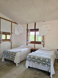 two beds in a room with two windows at La posada de Mary in Montañita