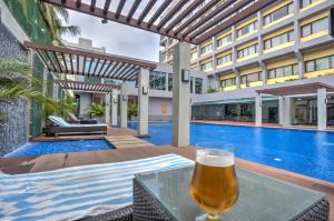 a glass of beer sitting on a table next to a swimming pool at Dolphin Hotel in Visakhapatnam