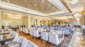 a restaurant with white chairs and tables in a room at New Century Grand Hotel Xinxiang in Xinxiang