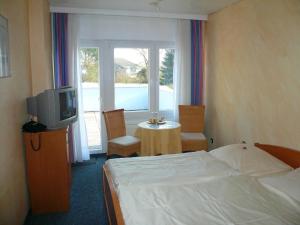 a bedroom with a bed and a tv and a table at Hotel-Restaurant Nord-Stuv in Cuxhaven