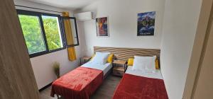 een kleine kamer met twee bedden en een raam bij Villa Rosie in Sainte-Rose +28 foto's
