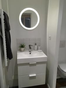 een witte badkamer met een wastafel en een spiegel bij Gîte Le Temple - Appart Hôtel in Verdun-sur-Meuse