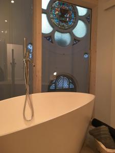 een badkamer met een bad en een glas-in-loodraam bij Gîte Le Temple - Appart Hôtel in Verdun-sur-Meuse