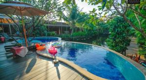 una piscina con sombrilla junto a un río en Panwana Resort, en Ban Taphong Nok