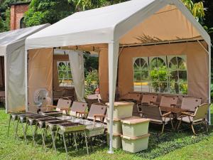 a tent with chairs and tables in the grass at 苗栗南庄 春友彩虹民宿SpringYU in Nanzhuang