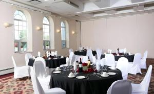 a room with white chairs and tables with black and white table settings at Coast High Country Inn in Whitehorse