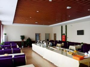 une grande pièce avec des chaises violettes et une longue table dans l'établissement GreenTree Inn Langfang GuAn County Xinyuan Street Express Hotel, à Gu'an