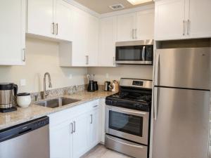 a kitchen with white cabinets and stainless steel appliances at Premier Resort Style Living Minutes from Santa Monica in Los Angeles