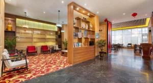 eine Lobby mit einer Bibliothek mit roten Stühlen und Tischen in der Unterkunft Metropolo Hotel YunNan Shangri-la Karma Dan Songzanlin Temple in Shangri-La