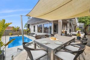 un patio con tavolo e sedie e una piscina di Manna Heaven Luxury Coastal Retreat with Pool a Torquay