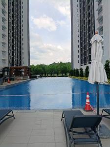 a pool with a umbrella and a table and chairs at Alstenor Homestay 2 in Kajang