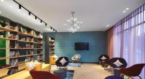 a living room with chairs and a tv and bookshelves at Campanile Hotel Huaibei Yuxi in Suixi
