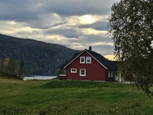 a red house in a field next to a lake at 7 person holiday home in Foldereid-By Traum in Årfor