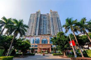 un grand bâtiment avec des palmiers devant dans l'établissement Manhatton Hotel Beihai, à Dianbailiao