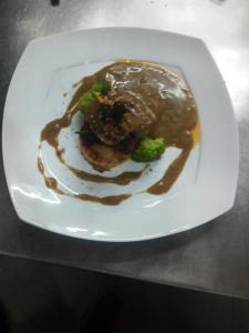 a plate with a piece of meat with gravy and broccoli at Noah's Yacht Farm in Siolim +30 photos