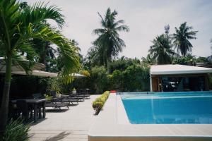 ein Swimmingpool mit Tischen und Stühlen und Palmen in der Unterkunft Point 303 Resort in General Luna