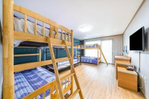 a room with two bunk beds and a television at Momento Hotel in Seogwipo