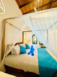 ein Schlafzimmer mit einem Bett mit blauen Kissen in der Unterkunft Coastal Cloud Surf - Walk To Dewata Beach in Unawatuna