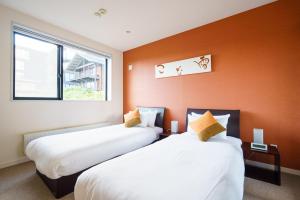 Dos camas en una habitación con una pared naranja. en Powder Haven, en Kutchan 11 fotos más