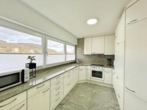 a kitchen with white cabinets and a large window at Basilisk Homes - in Grenzach-Wyhlen bei Basel - 4 x Moderne Fewos je 1bis2, 1bis4 oder 1bis6 Pers mit Küche und Balkon oder Terrasse - Parkplätze vorhanden in Grenzach-Wyhlen