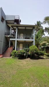 une maison avec un balcon et un palmier dans l'établissement Suki Beach Resort Standard Aircon Room D, à Santa Magdalena