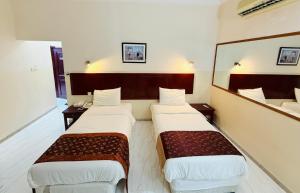 Una habitación de hotel con dos camas y un espejo. en Makran Palace Hotel, en Ma‘ābīlah