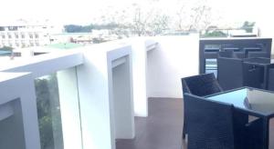 un balcon blanc avec des chaises et des tables sur un bâtiment dans l'établissement Avenue Suites, à Bacolod
