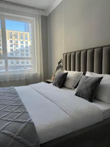 ein Schlafzimmer mit einem großen weißen Bett mit einem Fenster in der Unterkunft ЖК Only sun в 10 минутах от Аэропорта in Prigorodnyy