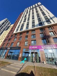 ein hohes Gebäude mit einem Schild davor in der Unterkunft ЖК Only sun в 10 минутах от Аэропорта in Prigorodnyy