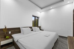 a white bedroom with a large white bed and a window at Ha Giang Hill Hotel in Dồng Văn