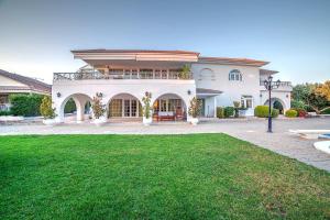 a large white house with a green lawn at Villa Noaina in Lagonissi in Lagonissi