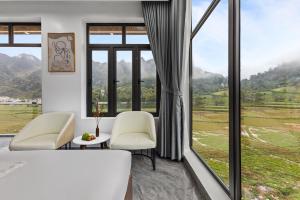 a room with a bed and chairs and a large window at Ha Giang Hill Hotel in Dồng Văn