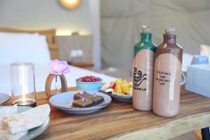a table with two bottles of water and a plate of food at Rabwa Geodesic Dome in Misfāh +18 photos