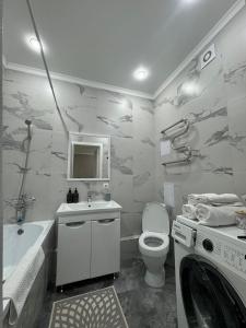 ein Badezimmer mit Waschbecken, Toilette und Waschmaschine in der Unterkunft ЖК Only sun в 10 минутах от Аэропорта in Prigorodnyy