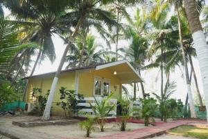 a yellow house with palm trees in front of it at Samant Beach Resort in Malvan