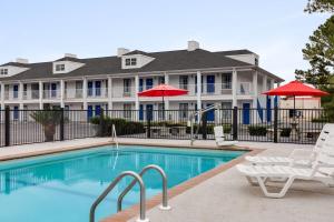 - une piscine avec des chaises et des parasols en face d'une maison dans l'établissement Baymont by Wyndham Albany at Albany Mall, à Albany