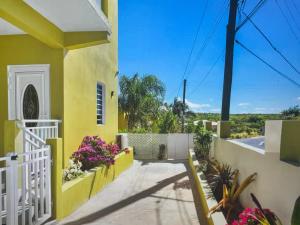una casa amarilla con una valla blanca y flores en Tropical paradise, 