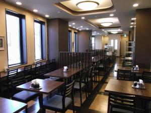 un restaurant avec des tables et des chaises en bois et des fenêtres dans l'établissement Hotel Route Inn Hirosaki Ekimae, à Hirosaki