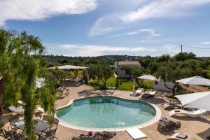 ein Swimmingpool mit Liegestühlen und ein Resort in der Unterkunft Trulli Rosalinda Luxury in Antonelli